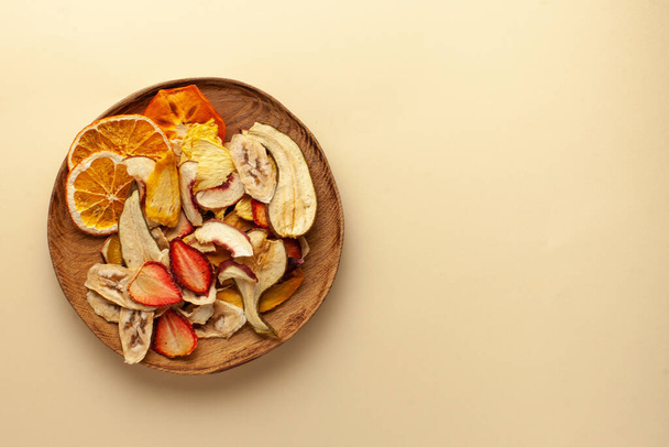  Chips de frutas secas en un plato de madera. El concepto de un bocadillo saludable sin azúcar, postre para vegetarianos. Copiar espacio. Aplanado
 - Foto, Imagen