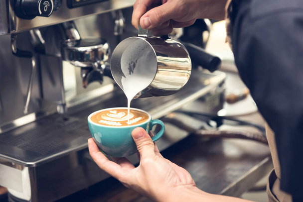 美しいラテアートを作るコーヒーカップに蒸しミルクを注ぐプロバリスタロゼッタパターン - 写真・画像