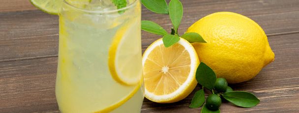 Succo di limonata rinfrescante bevanda nel bicchiere con limoni su sfondo tavolo in legno, dimensione banner
 - Foto, immagini
