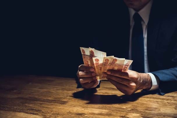 Üzletember a sötét szobában számolja a pénzt, orosz rubel valuta - Fotó, kép