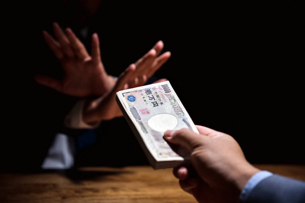 Uomo d'affari che rifiuta il denaro, valuta yen giapponese, offerto dal suo partner in camera oscura - concetto anti birbery e corruzione
 - Foto, immagini