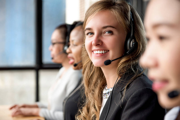 Friendly beautiful caucasian woman telemarketing customer service agent working in call center with her multiethnic team - Photo, Image