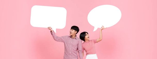 Happy smiling young Asian couple with speech bubbles studio shot on pink banner background - Photo, Image