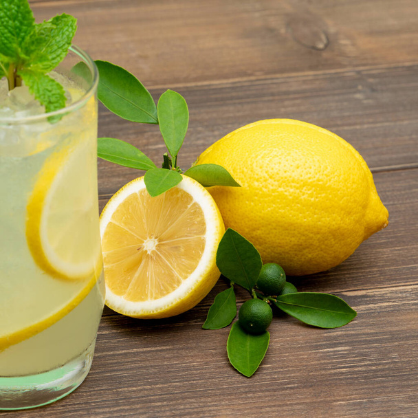 Refrescante bebida de jugo de limonada en el vaso con limones sobre fondo de mesa de madera
 - Foto, imagen
