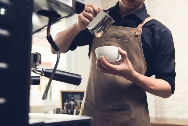Profesional barista verter leche al vapor en la taza de café haciendo arte latte en la cafetería
 - Foto, Imagen
