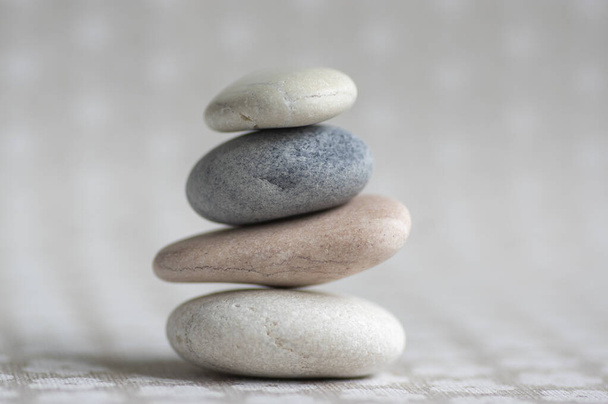 Stone cairn on striped grey white background, four stones tower, simple poise stones, simplicity harmony and balance, rock zen sculpture - Zdjęcie, obraz