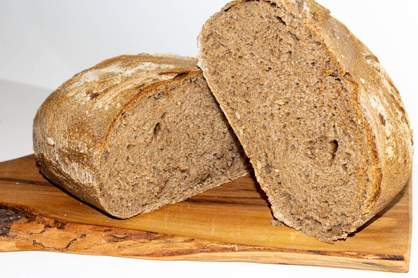 černý obilný chléb uložený na řezací desce. - Fotografie, Obrázek