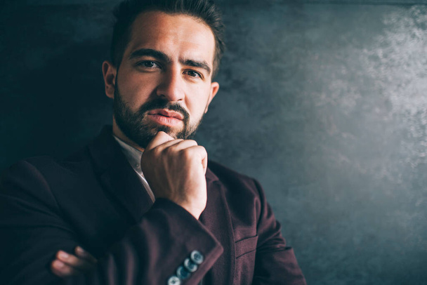Portrait of handsome caucasian businessman in formal outfit pondering on idea for project feeling confident, serious successful male entrepreneur dressed in luxury clothes looking at camera near wall - Foto, imagen