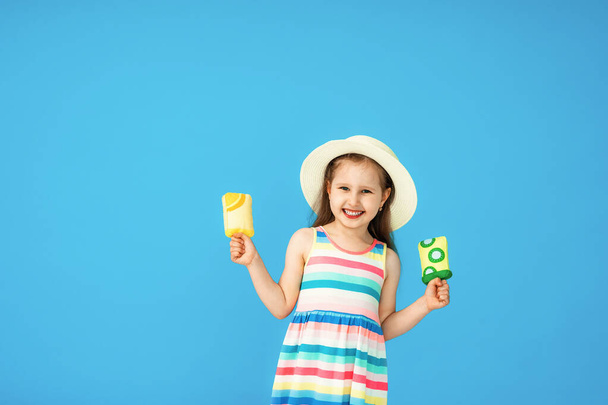 concept of summer and a cool dessert. Portrait of a beautiful happy little girl in a straw hat with textile ice cream on a blue background - Foto, Imagen