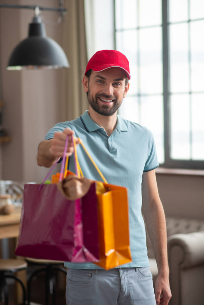 Delivery person in a red hat holding shopping bags - Foto, Imagem
