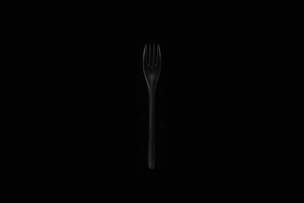 isolated black fork on black background horizontal top view - Zdjęcie, obraz