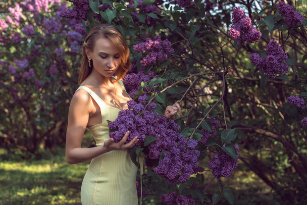 Wandeling met een jonge vrouw in het lila bloeiseizoen - Foto, afbeelding