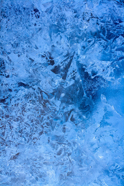 Καταπληκτικό φόντο υφή πάγου. Γαλάζια λίμνη πάγου με ρωγμές και παγωμένες φυσαλίδες αέρα. Κάθετη.. - Φωτογραφία, εικόνα