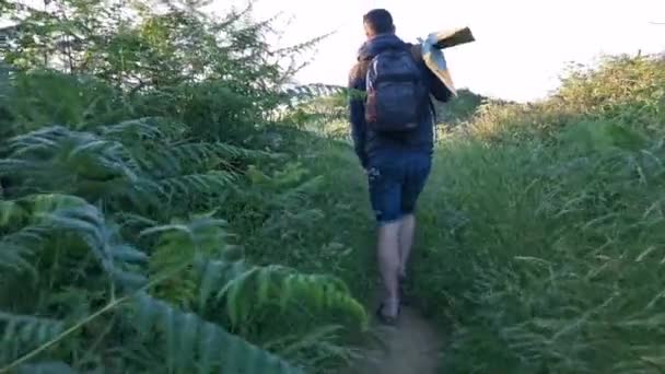 Jovem com mochila e barbatanas nas mãos caminhando em caminhos perto da costa
 - Filmagem, Vídeo