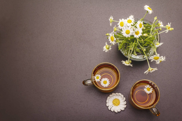 Papatya çayı. Taze çiçekler, yaz sıcak içecek konsepti. Alternatif tıp, yaşam tarzı. Moda siyah taş arka plan, üst görünüm - Fotoğraf, Görsel