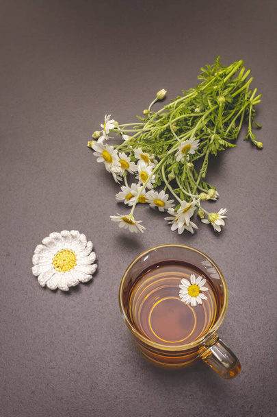 Papatya çayı. Taze çiçekler, yaz sıcak içecek konsepti. Alternatif tıp, yaşam tarzı. Moda siyah taş arka plan, üst görünüm - Fotoğraf, Görsel