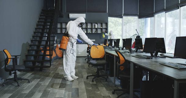 Mannen in hazmat pakken desinfecteren kantoor - Foto, afbeelding