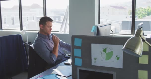 Side view of a Caucasian male business creative working in a casual modern office, using a computer, looking out of the window and thinking in slow motion - Filmmaterial, Video