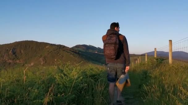 Fiatal férfi hátizsákkal és uszonyokkal a kezében, a part menti ösvényeken sétál. - Felvétel, videó