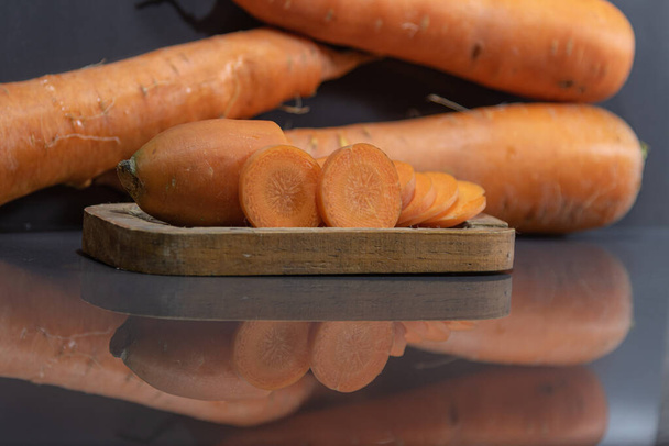Carrot (Daucus carota) in natura. Vegetable for salads. Wooden tray. Vegetable used in Brazilian cuisine. Delicacy. plant belonging to the Apiaceae family. Orange tuberous root. - Photo, Image