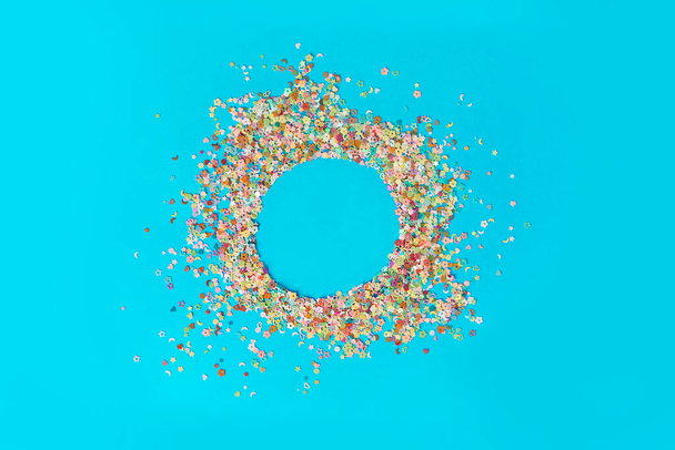 Round frame made of colored confetti. blue background. Festive confetti. - Photo, Image