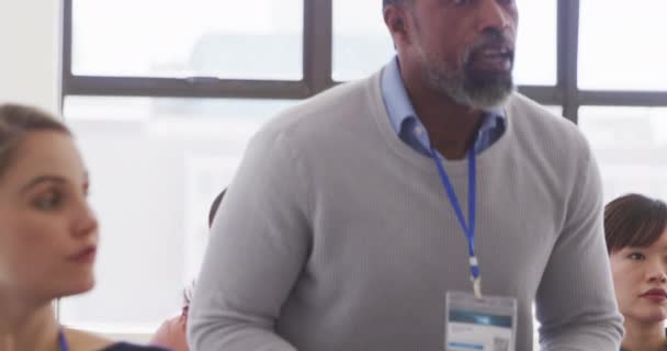 Front view of an African American male business creative taking part in a business conference, standing and asking a question, with colleagues sitting in the background in slow motion - Filmagem, Vídeo