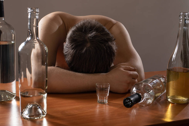 Humalainen mies ja tyhjät pullot. Alkoholismi, riippuvuus, kriisi ja masennus
. - Valokuva, kuva