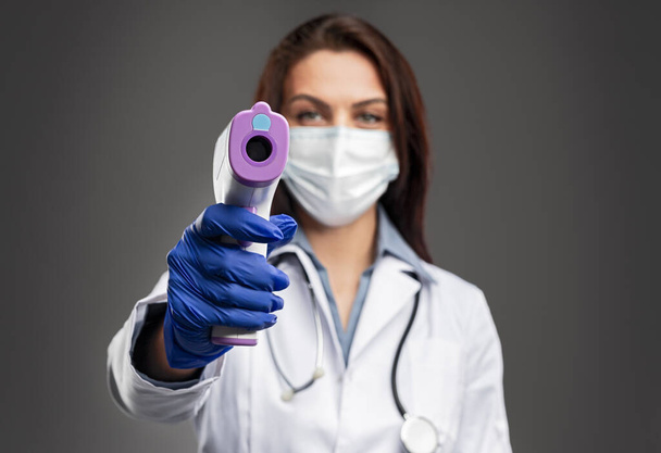 Female doctor measuring temperature with infrared thermometer - Photo, image