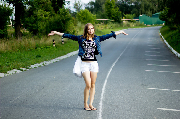 Joven mujer feliz con una bolsa en un camino
 - Foto, Imagen