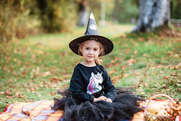 Halloween. Girl in a costume for Halloween. Happy teenager smiling. Autumn portrait of a beautiful young girl. in the background - a basket of apples and pumpkin. - Foto, Bild