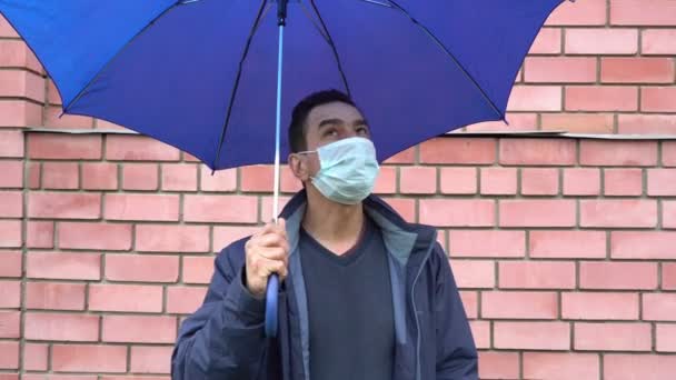 Triste hombre enmascarado parado solo bajo el paraguas, distancia social, autoaislamiento, cuarentena
 - Imágenes, Vídeo