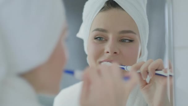 Young woman brushing teeth looking at mirror at home bathroom.  Dental care and hygiene - Metraje, vídeo