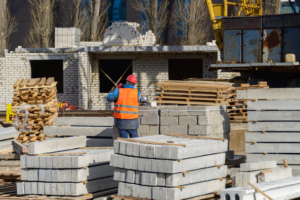 Huizenbouw. Een arbeider loopt op een bouwplaats. De betonnen plaat voor de bouw van de gebouwen bevindt zich op het terrein. - Foto, afbeelding