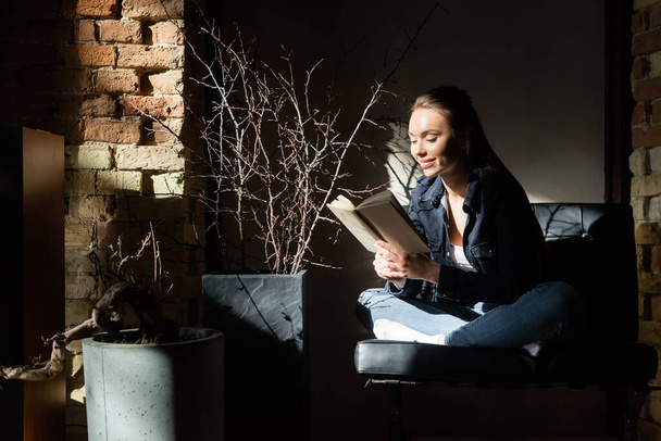 sunlight on cheerful young woman reading book  - Фото, зображення