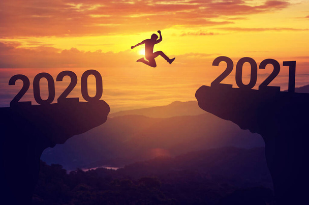 Silhouette homme saut entre 2020 et 2021 ans avec fond de coucher de soleil, Succès nouveau concept année
. - Photo, image