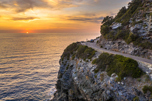 Carretera sinuosa a lo largo de la costa rocosa de la península de Cap Corse en la isla de Córcega al atardecer, Francia - Foto, imagen