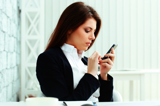 Businesswoman typing on her smartphone - Valokuva, kuva