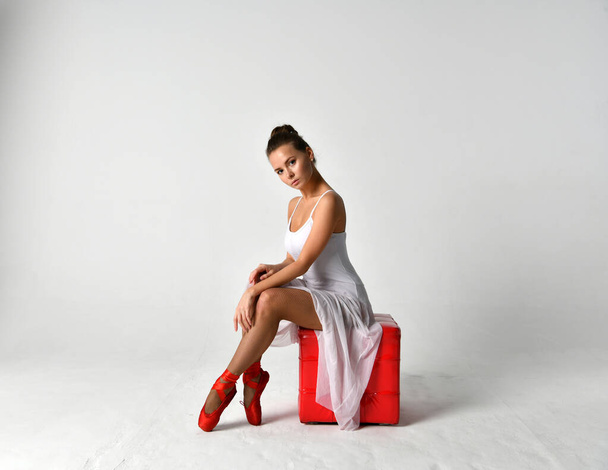 ballerina in a white dress and red pointes and a red cube - Valokuva, kuva