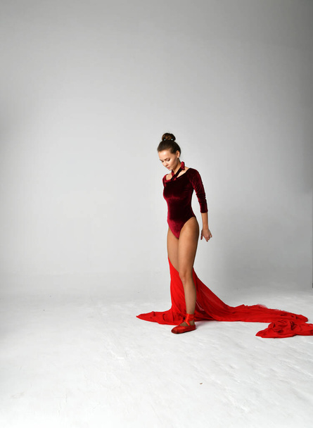 γυμνάστρια με κόκκινη στολή που χορεύει με κόκκινο παρεό σε λευκό φόντο - Φωτογραφία, εικόνα