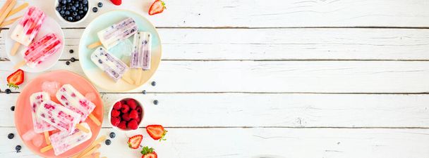 Variedade de picolés de iogurte de frutas silvestres. Acima da borda lateral da cena da tabela de exibição em um fundo de banner de madeira branca com espaço de cópia
. - Foto, Imagem