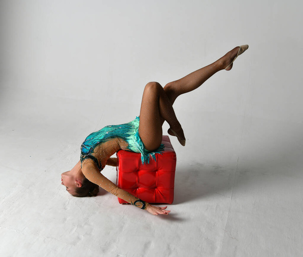 gimnastyczka w niebieskim garniturze i czerwona kostka na białym tle - Zdjęcie, obraz