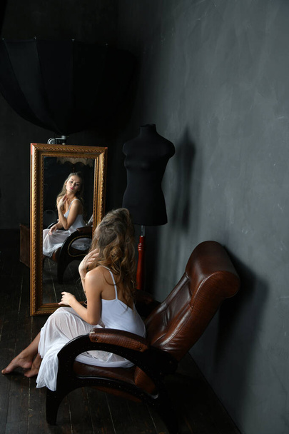 balerina w białej sukience i czerwone punkty siedzi na brązowym krześle i patrzy w lustro - Zdjęcie, obraz