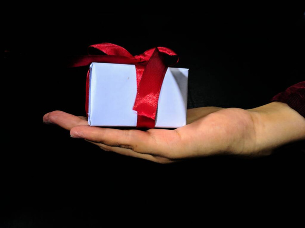 ruce držící dárkovou krabici s červenou stuhou - Fotografie, Obrázek
