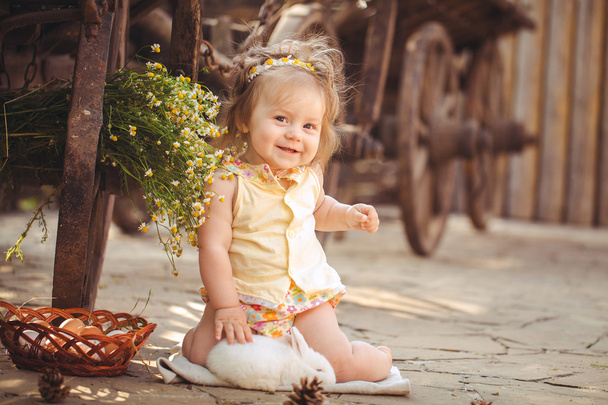 Little girl playing with rabbit in the village. Outdoor. Summer portrait. - Foto, imagen