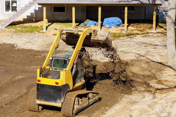 Mini travaux d'aménagement paysager bulldozer sur la construction de travailler avec la terre tout en faisant excavatrice scoop
 - Photo, image