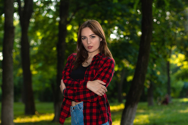 Girl in plaid shirt. Cute young woman in summer park - Foto, immagini