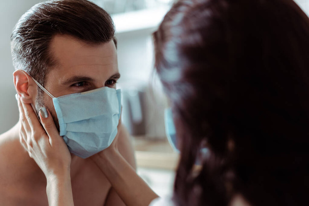 selective focus of woman touching sexy young man in medical mask - Fotografie, Obrázek