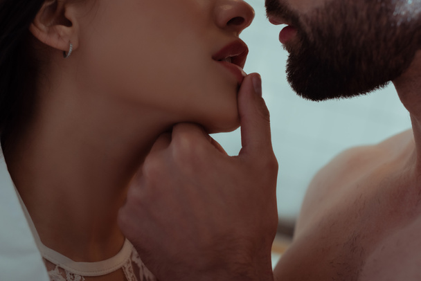 セクシーな若い女性の唇に触れる男のクローズアップ - 写真・画像