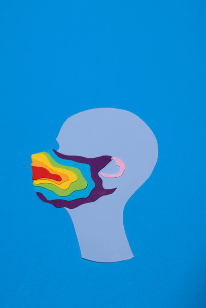 Silueta de un hombre con máscara de arco iris, hecha de papel, sobre un fondo azul
 - Foto, imagen