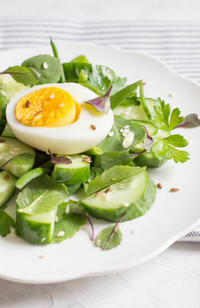 Свежий огуречный салат с микро зеленью и яйцом. Потрясающая еда. Вид сверху, лежащий плоский, крупный план
 - Фото, изображение